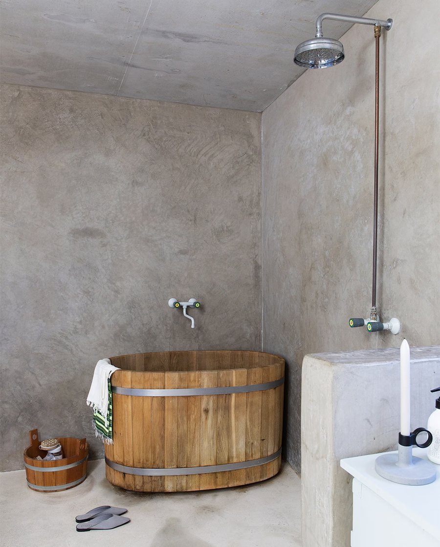 Badkamer met beton cire wanden en een houten bad