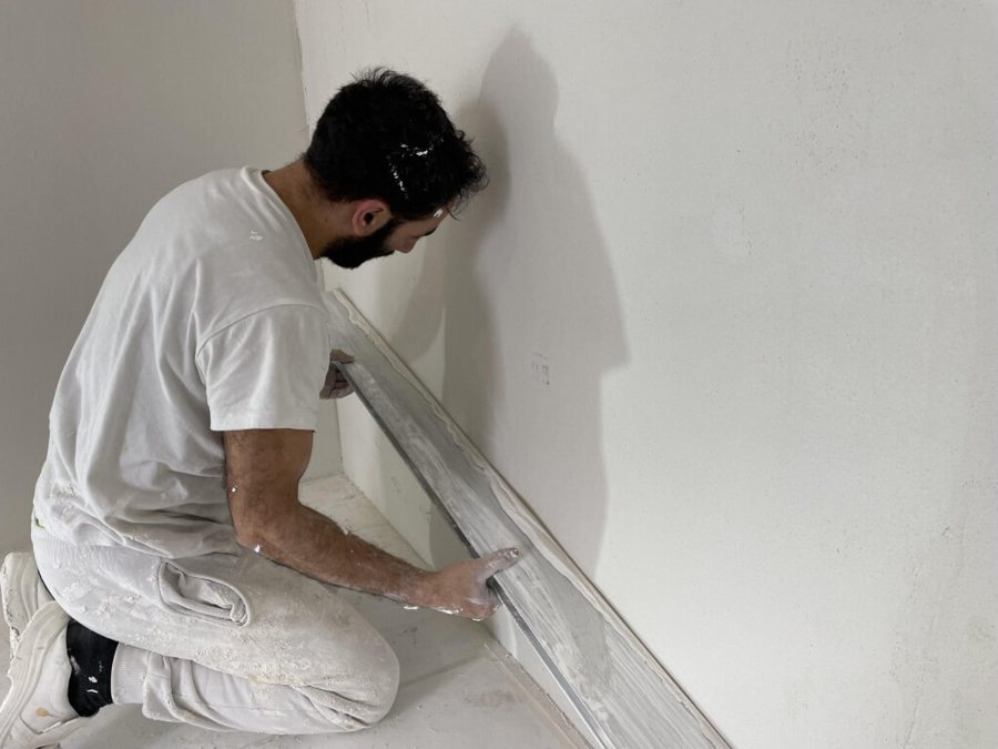 Stukadoor werkt een muur glad met een rei