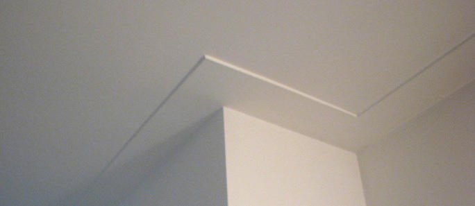 Strak wit gestuukt plafond met een nette plafondplint